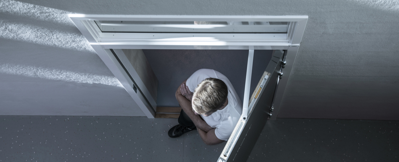 Bilden visar en person ovanifrån. Personen går genom en öppnad dörr.